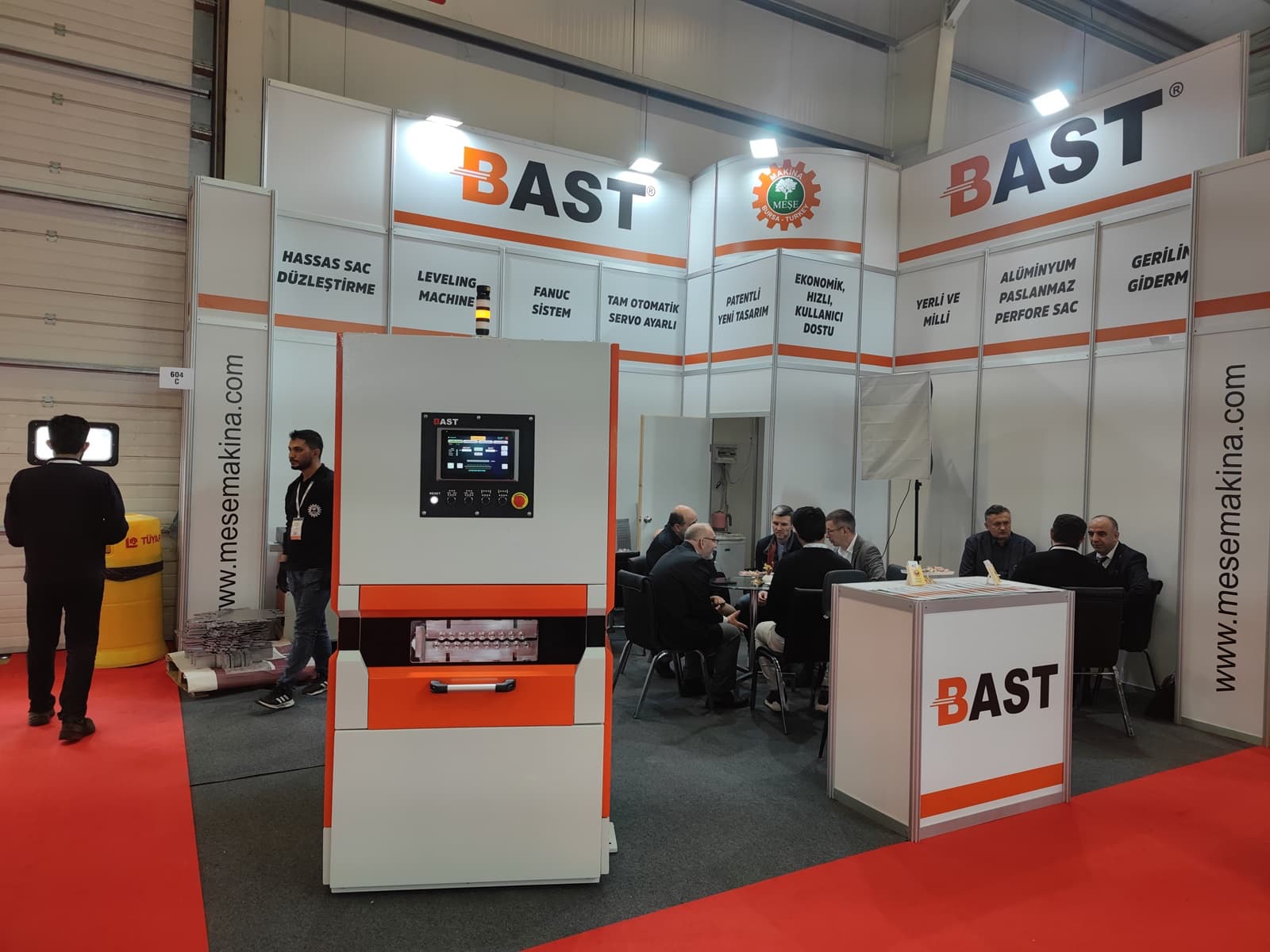 Stand BAST in fiera con macchina raddrizzatrice per lamiere metalliche e incontri commerciali nel settore industriale