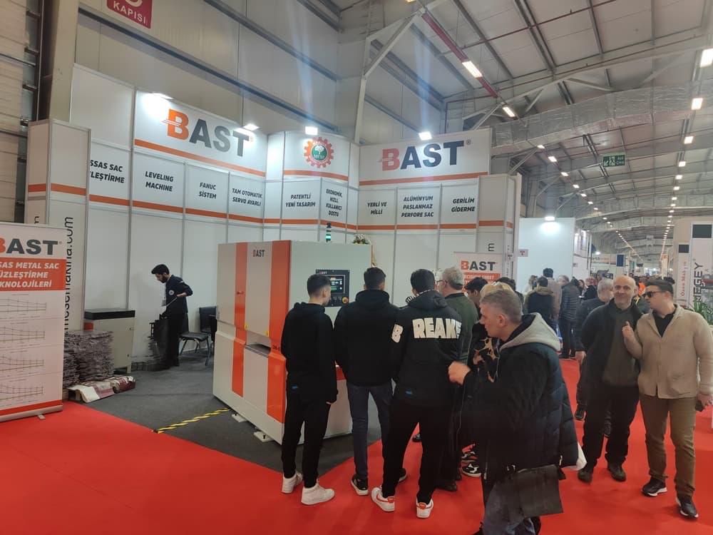 bast-sac-duzeltme-makinesi-fuar-standi BAST sac düzeltme makinesi, endüstriyel makine fuarında ziyaretçiler tarafından incelenirken